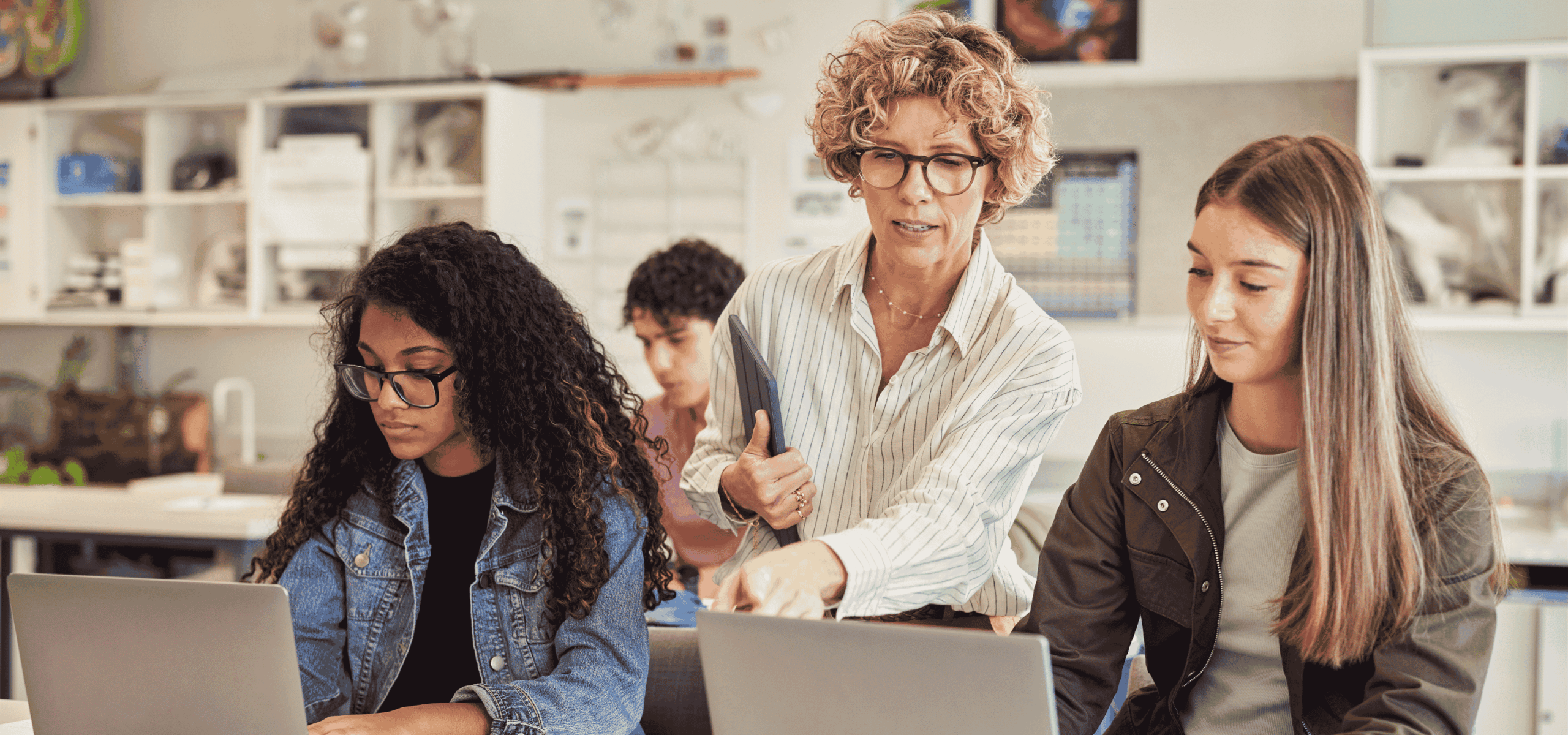 teacher working with students who are on a laptop