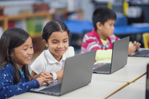 3 students working on laptops in a classroom learning